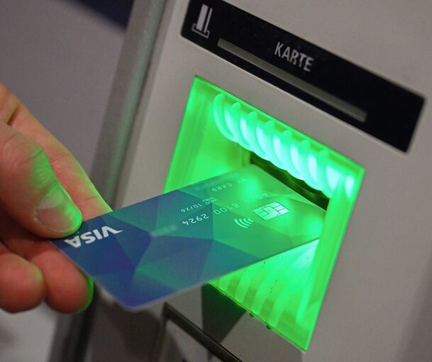 Ein Flüchtling hält eine Karte vor einen Bankautomaten: Die FDP fordert, auch im Landkreis eine Bezahlkarte für Schutzsuchende – um ihnen die Möglichkeit zu nehmen, Geld ins Herkunftsland zu überweisen. Foto: dpa
