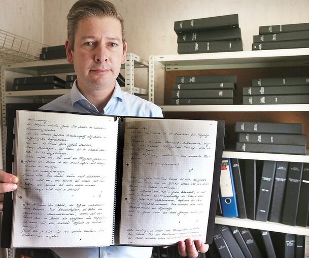 Der Sammler Oliver Boger mit dem von Kujau in seiner Handschrift geschriebenen letzten Band der „Hitler-Tagebücher“. Im Hintergrund die Gerichts-und Vernehmungsakten des Gerichtsprozesses in Hamburg im Archiv von Oliver Boger.