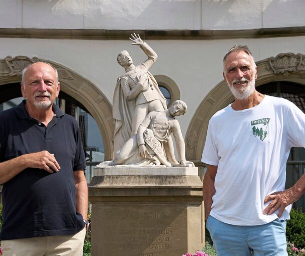 Erhard Korn (links) und Gerhard Jüttner vor dem „Taube-Denkmal“ in Pleidelsheim, das den Kriegstod zweier Brüder verherrlicht.