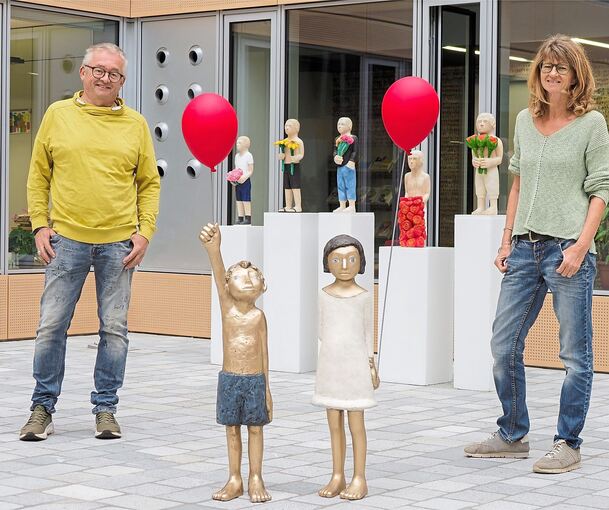 Zwei Kinder mit Ballons, dahinter fünf „Möchtegern-Coolys“ mit Blumen: Tamara Suhr und Peter Hermann stellen im Atrium des Erweiterungsbaus des Landratsamtes aus.