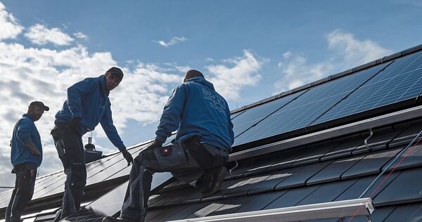 Handwerker bringen eine PV-Anlage auf einem Hausdach an. Handwerker bringen eine PV-Anlage auf einem Hausdach an.
