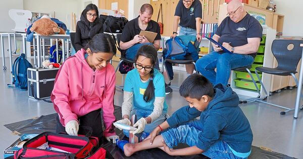 Die jungen Helferinnen und Helfer versorgen unter Beobachtung der Schiedsrichter eine Schürfwunde. Die jungen Helferinnen und Helfer versorgen unter Beobachtung der Schiedsrichter eine Schürfwunde.
