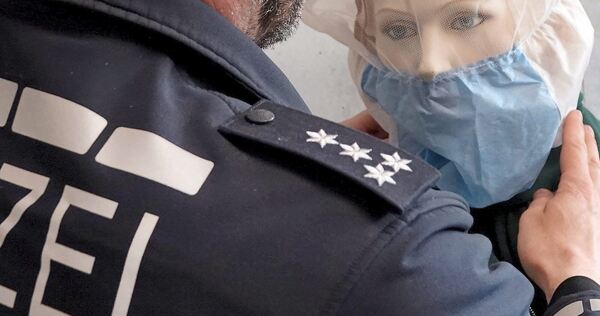 Ein Polizist demonstriert die Anwendung einer Spuckschutzhaube an einer Puppe. Ein Polizist demonstriert die Anwendung einer Spuckschutzhaube an einer Puppe.